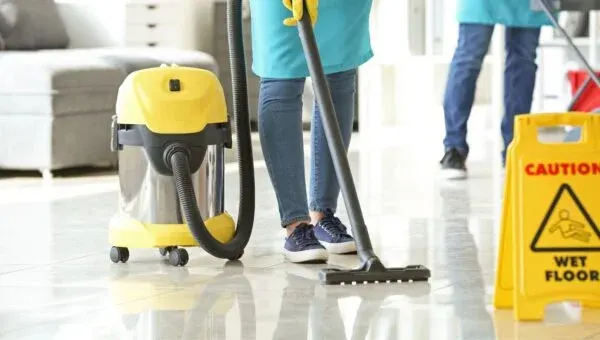 Office floor being cleaned beside a wet floor sign