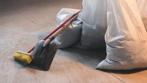 Broom and debris bags on a dusty floor after building work