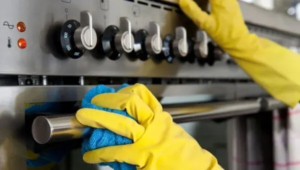 Gloved hand wiping down an oven door